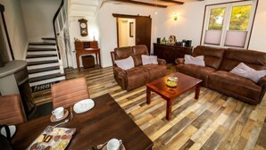 Un vaste espace de vie doté d’un plancher en bois, de canapés en cuir, d’une table basse et d’une table à manger dressée avec des assiettes et des tasses.