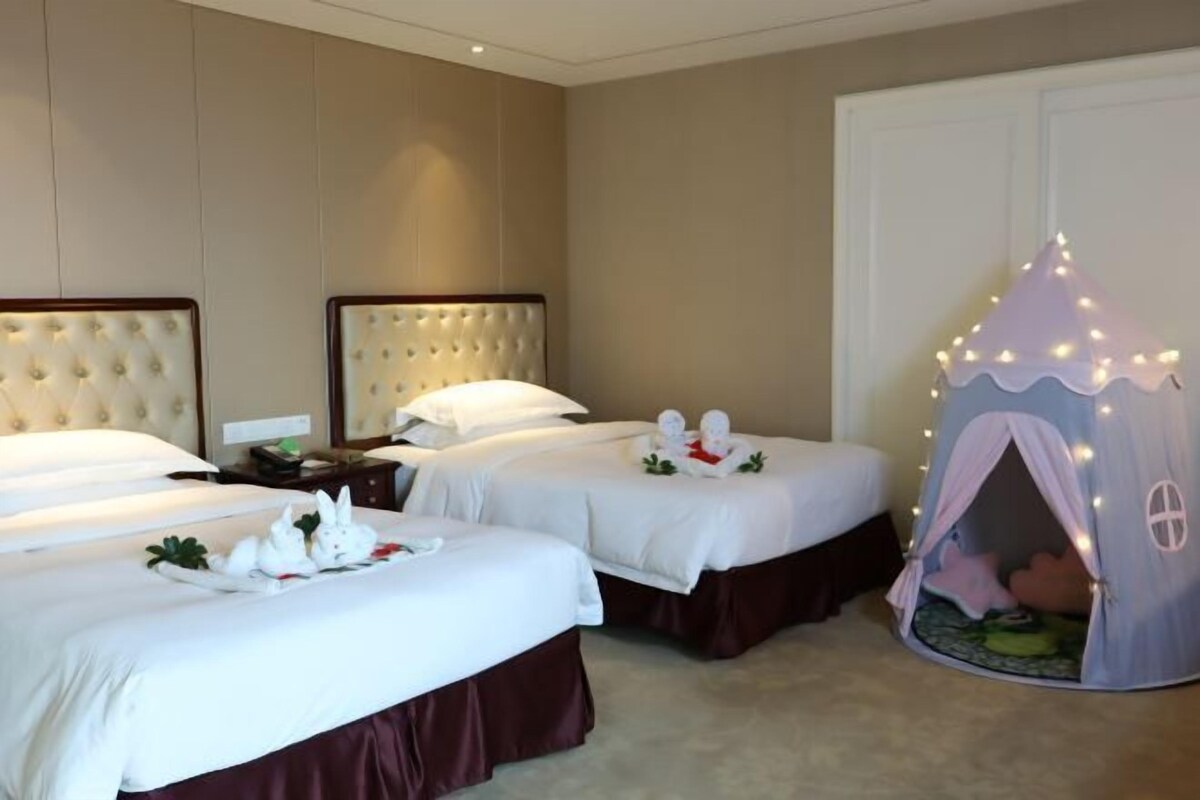Habitación de hotel con dos camas, un área de juegos tipo tienda de campaña y un minibar.