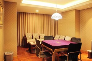 A hotel room with a dining table, chairs, a sofa, and a chandelier.