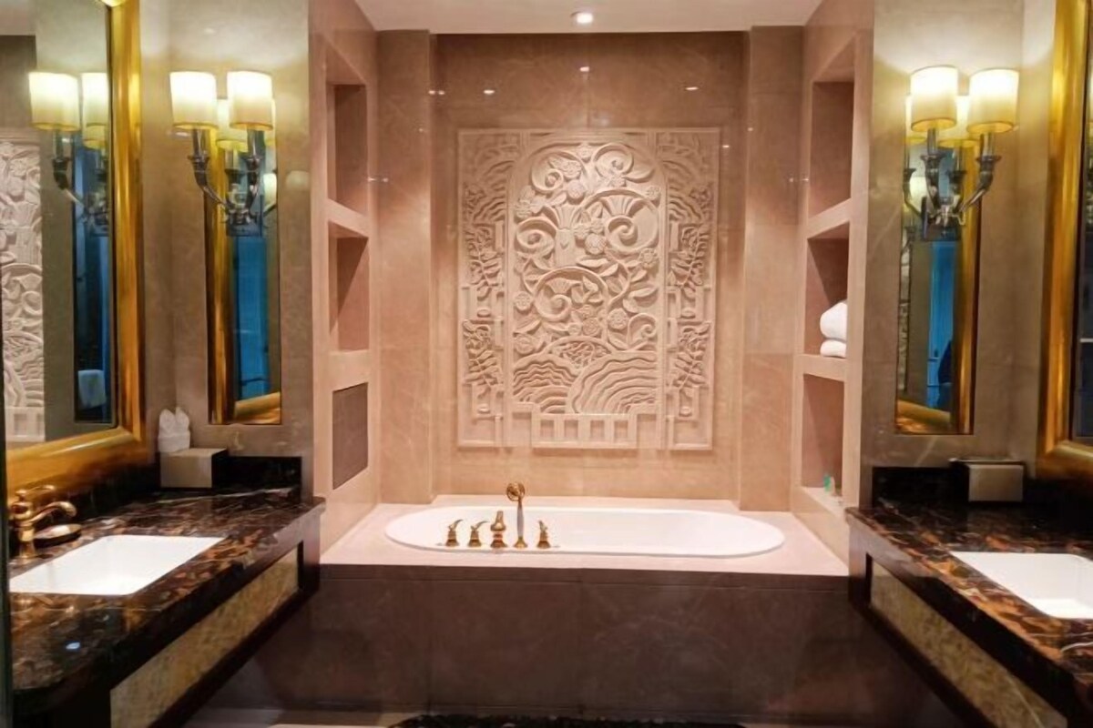 Un baño lujoso con una bañera central, dos lavamanos y paneles decorativos en las paredes.