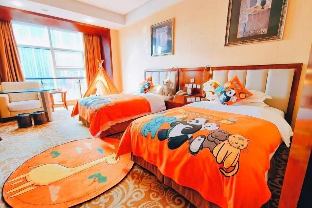 A hotel room with two beds, a sofa, a dining table, and a window with curtains.