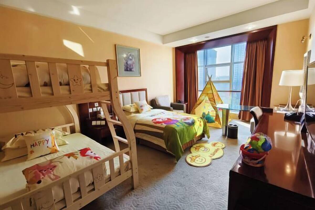 A child-friendly hotel room with bunk beds, a play area, and a desk.