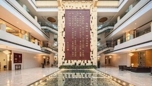A spacious atrium with a central decorative wall, multiple floors, and a polished marble floor. - Minjiang Donghu Hotel (Meishan)