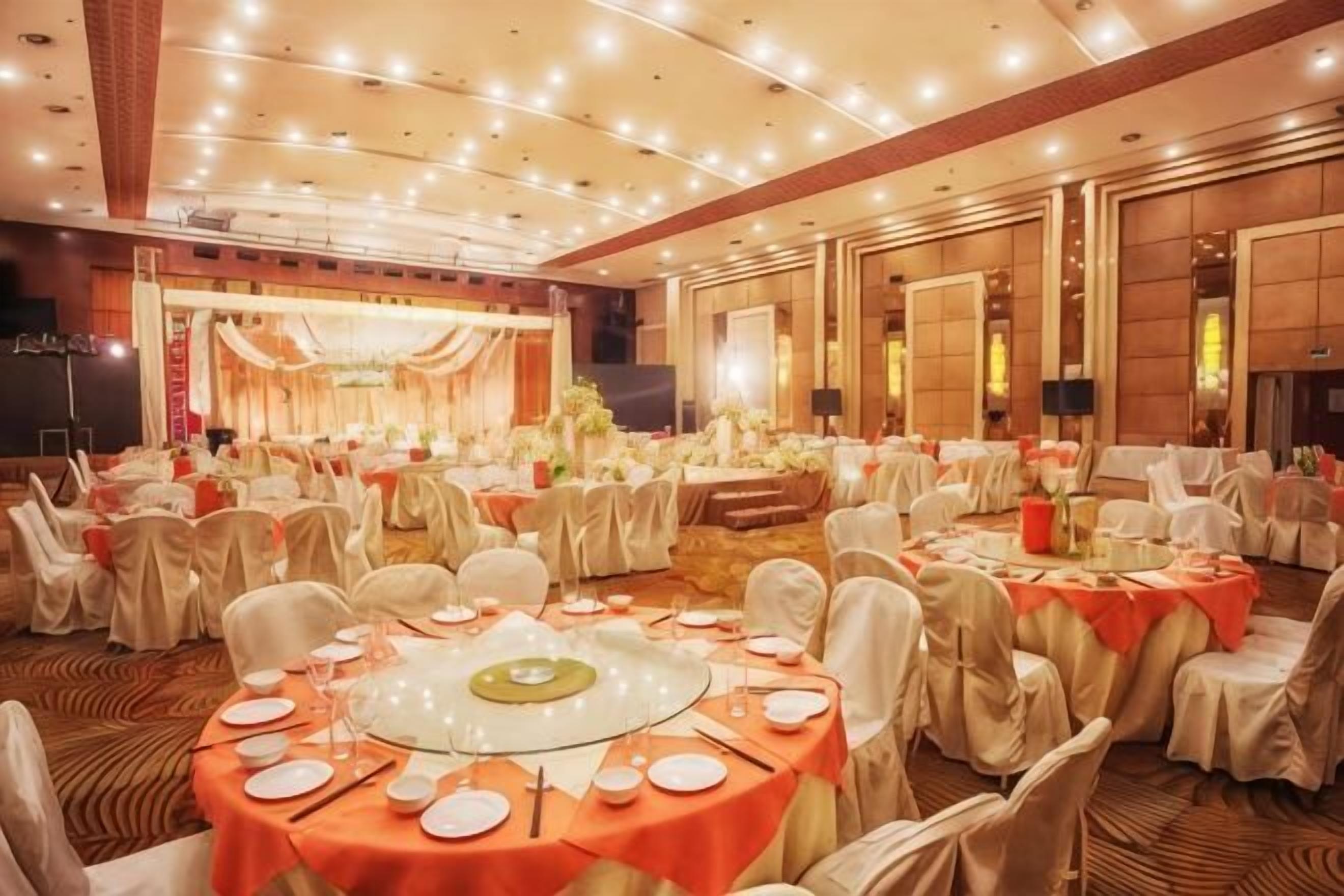 A banquet hall with round tables, chairs, and a stage.