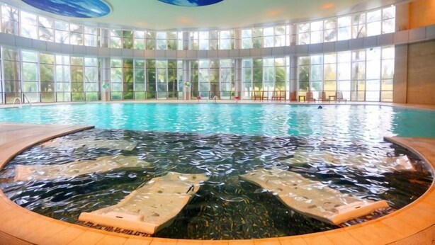 A large indoor swimming pool with a hot tub, surrounded by large windows and a circular ceiling design. - Minjiang Donghu Hotel (Meishan)
