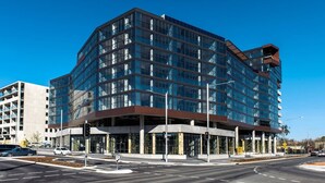 Un immeuble moderne à plusieurs étages, doté d’une façade en verre, situé à un carrefour.