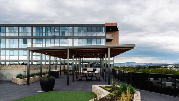 Une terrasse sur le toit avec des sièges extérieurs, une vue sur le paysage urbain et un bâtiment moderne en arrière-plan.