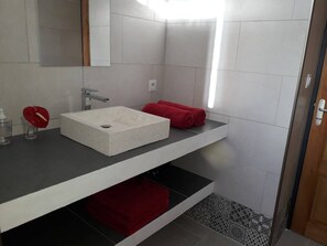 Een moderne badkamer met een wit wastafelmeubel, een spiegel en een rode handdoek op een plank.