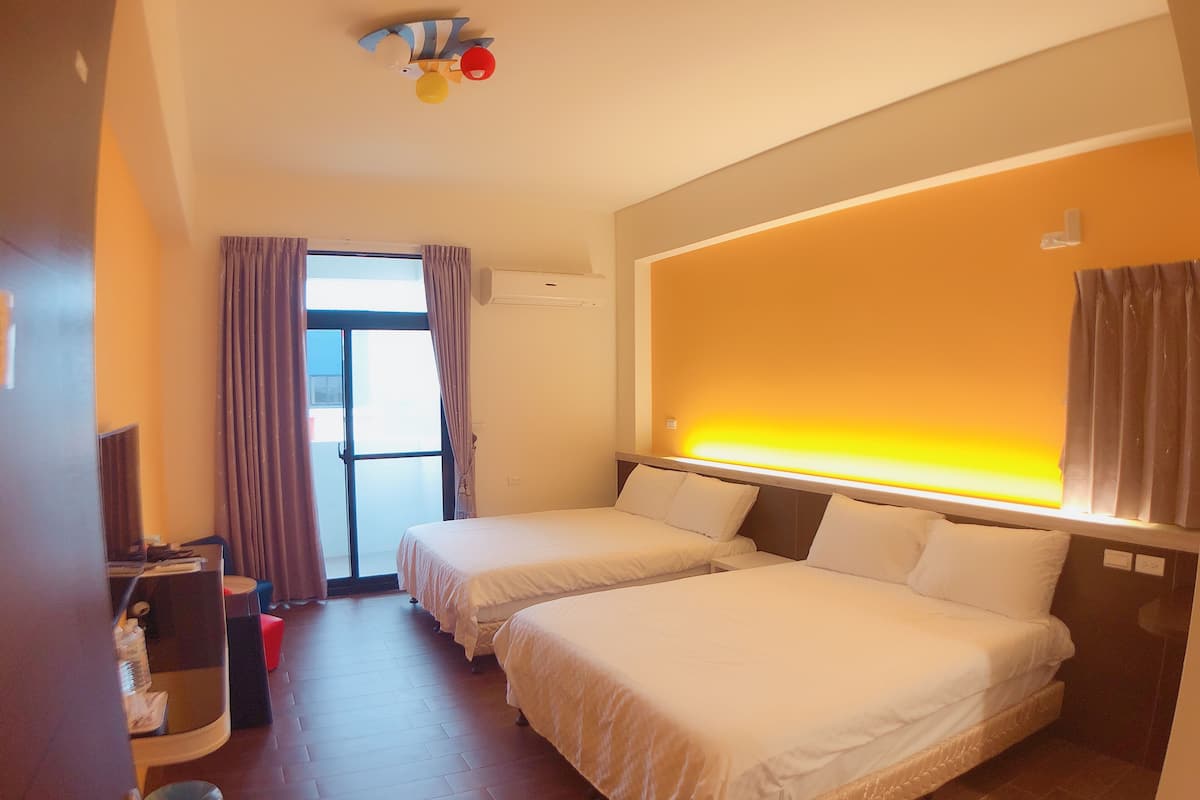 A hotel room with two beds, a desk, a chair, and a window with curtains.