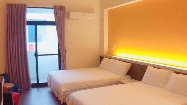 A hotel room with two beds, a desk, and a window with curtains.