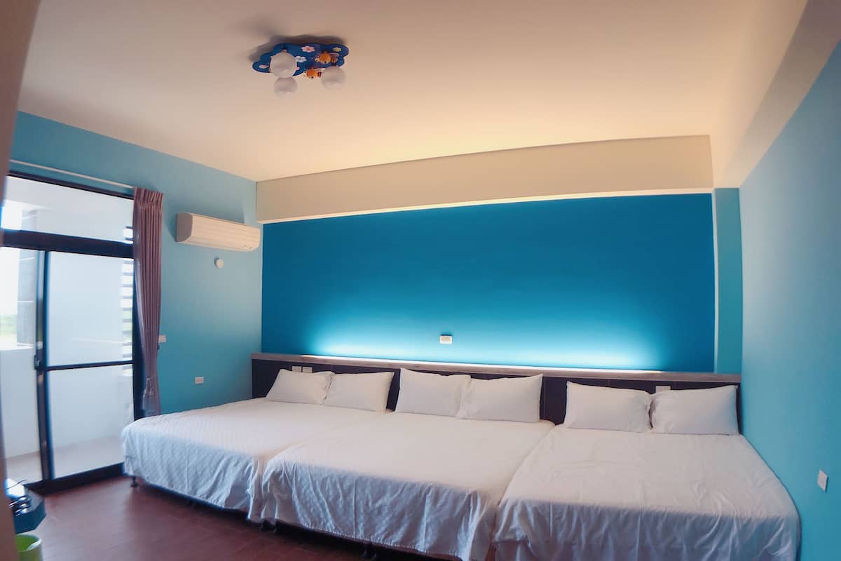 A hotel room with a large bed, a ceiling fan, and a window with curtains.