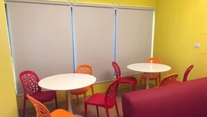 A room with two round tables and multiple chairs, a red sofa, and a large whiteboard.