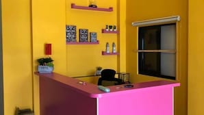 A reception area with a pink counter, yellow walls, and a window with blinds.