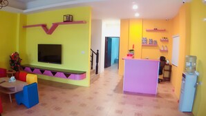 A brightly colored living room with a TV mounted on a wall, a sofa, a coffee table, and a small table with a plant.