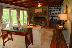 Una habitación acogedora con una mesa de madera, un banco acolchado, una chimenea y una estantería con cerámica.