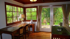 Una habitación con una mesa de comedor de madera, sillas, una lámpara y vistas al exterior a través de amplias ventanas.