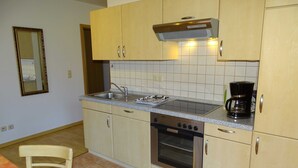 Eine kleine Küche mit Herd, Backofen, Spüle und Kaffeemaschine.