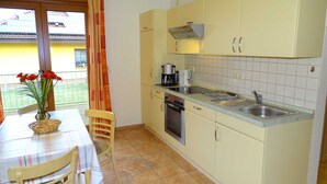 A compact kitchen with a dining area, featuring a table, chairs, a sink, and a stove. - Vacation apartment 2 - Kos - Holiday home Ohm (Koserow)