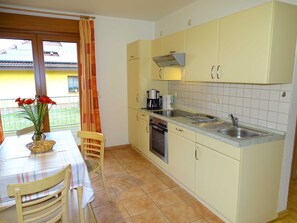 Une cuisine compacte avec un coin repas, comprenant une table, des chaises, un évier et une cuisinière.