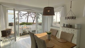 Un coin repas avec une table en bois, des chaises en osier et un luminaire suspendu.