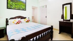 A hotel room with a bed, a dresser, a mirror, and a painting on the wall. - Wonder Hill Residency (Ootacamund)