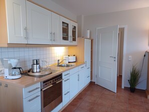 Eine moderne Küche mit weißen Schränken, einem Einbauofen, einer Kaffeemaschine und einem Spülbecken.