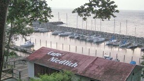 Un pequeño edificio de techo rojo con el letrero "Cafe Niedlich" cerca de un puerto deportivo con varias embarcaciones amarradas.