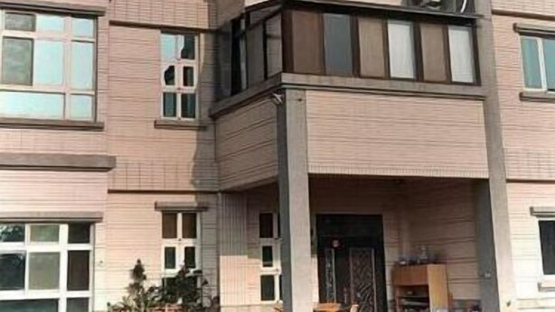 A multi-story building with a modern architectural design, featuring a prominent entrance with a decorative door and a small balcony area. - Kinmen Good Friends (Jincheng)