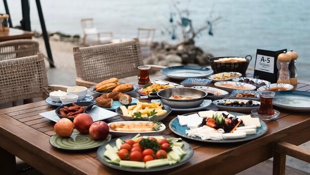 A table set with various dishes and a view of the sea. - Mykonut Apart Hotel (Fethiye)