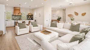 Una sala de estar moderna con un sofá, sillas, una mesa de centro y un comedor con mesa y sillas.