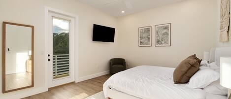 A bedroom with a bed, a ceiling fan, a TV, and artwork on the wall.