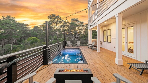 Una terraza con piscina, mobiliario exterior y una chimenea.