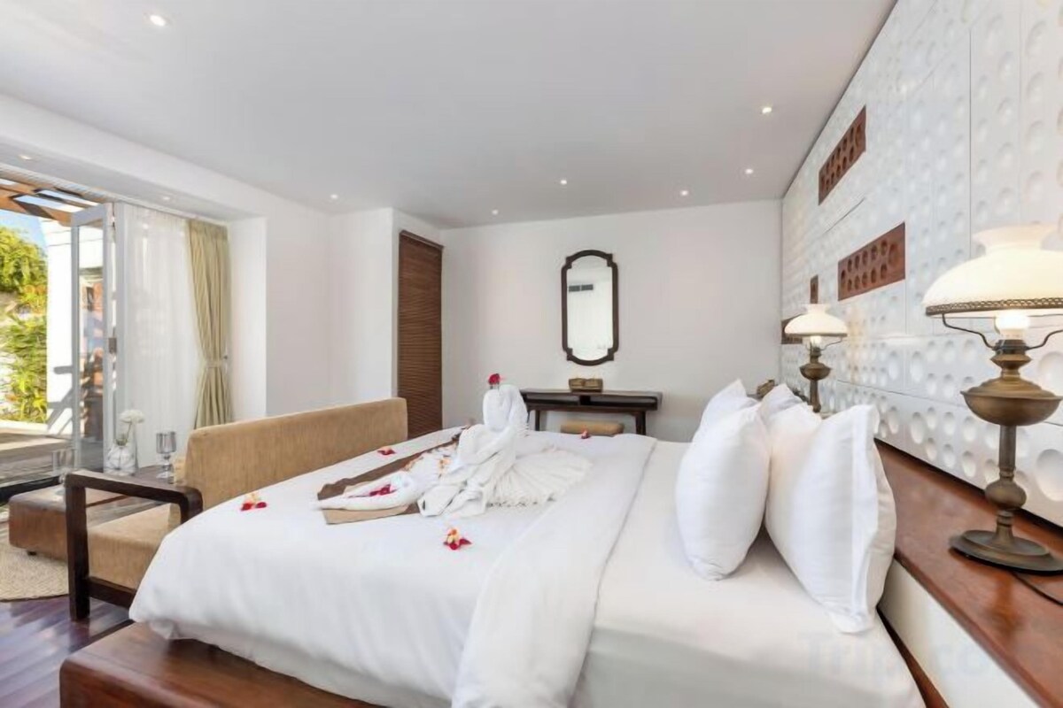 A hotel room with a large bed, a sofa, a desk, and a view of the outdoors.