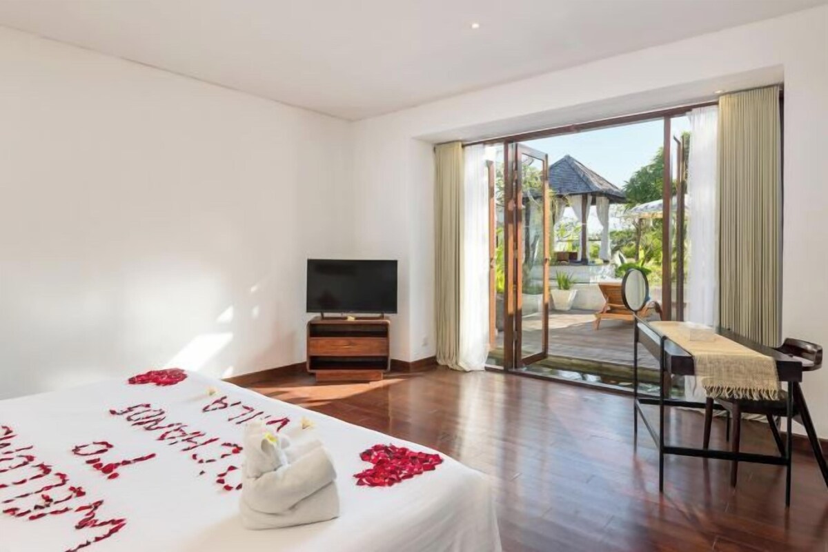 Quarto de hotel com cama, televisão, área de refeições e vista para o exterior.