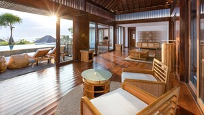 A spacious indoor area with wooden flooring, a glass door leading outside, and a seating area with cushioned chairs and a round table.