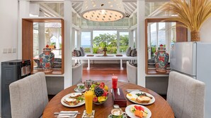 A dining area with a wooden table set for breakfast, surrounded by chairs, with a view of the outdoors.