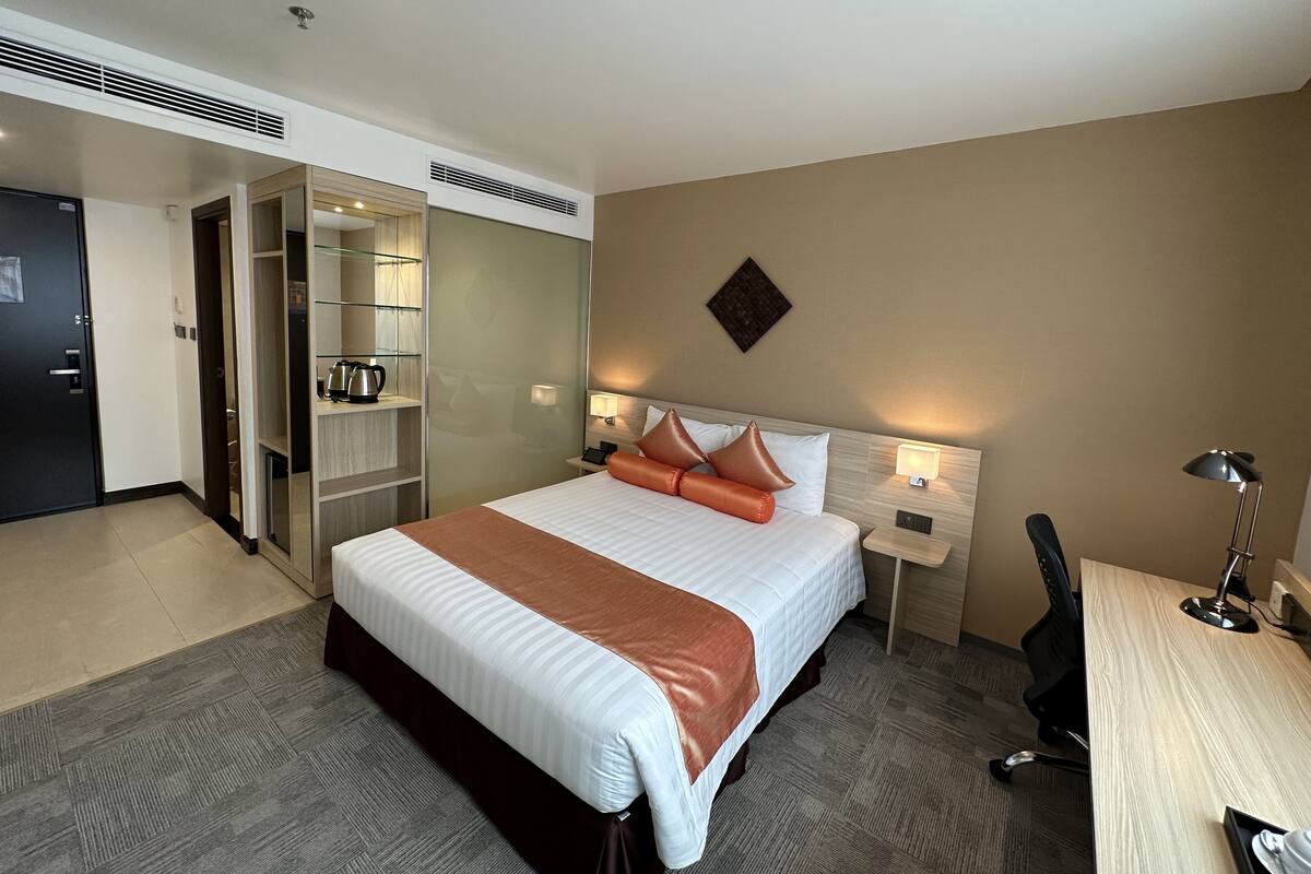Une chambre d’hôtel avec un grand lit, des tables de chevet, un bureau et une armoire.