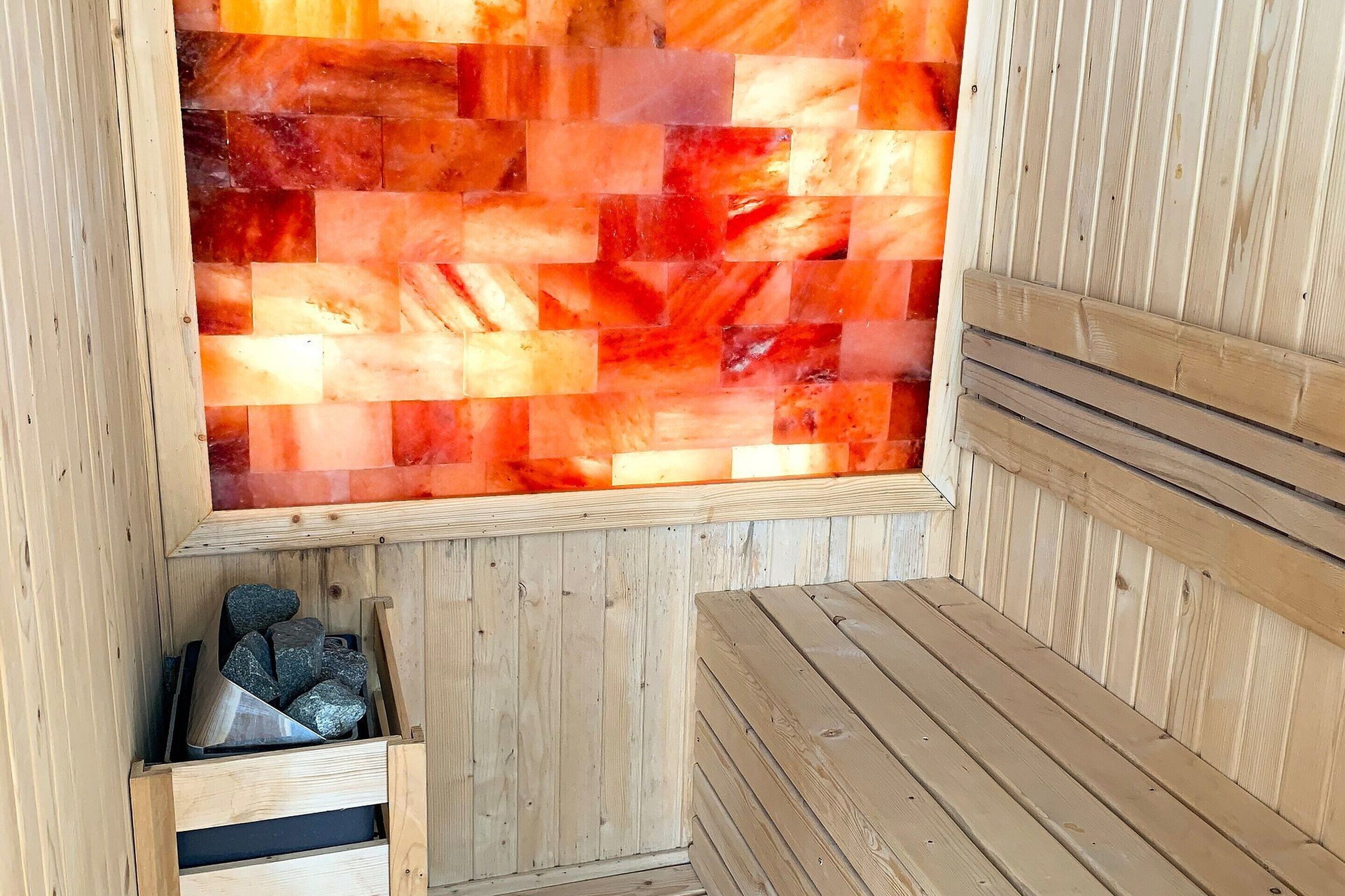 A sauna with wooden benches and a mosaic wall.