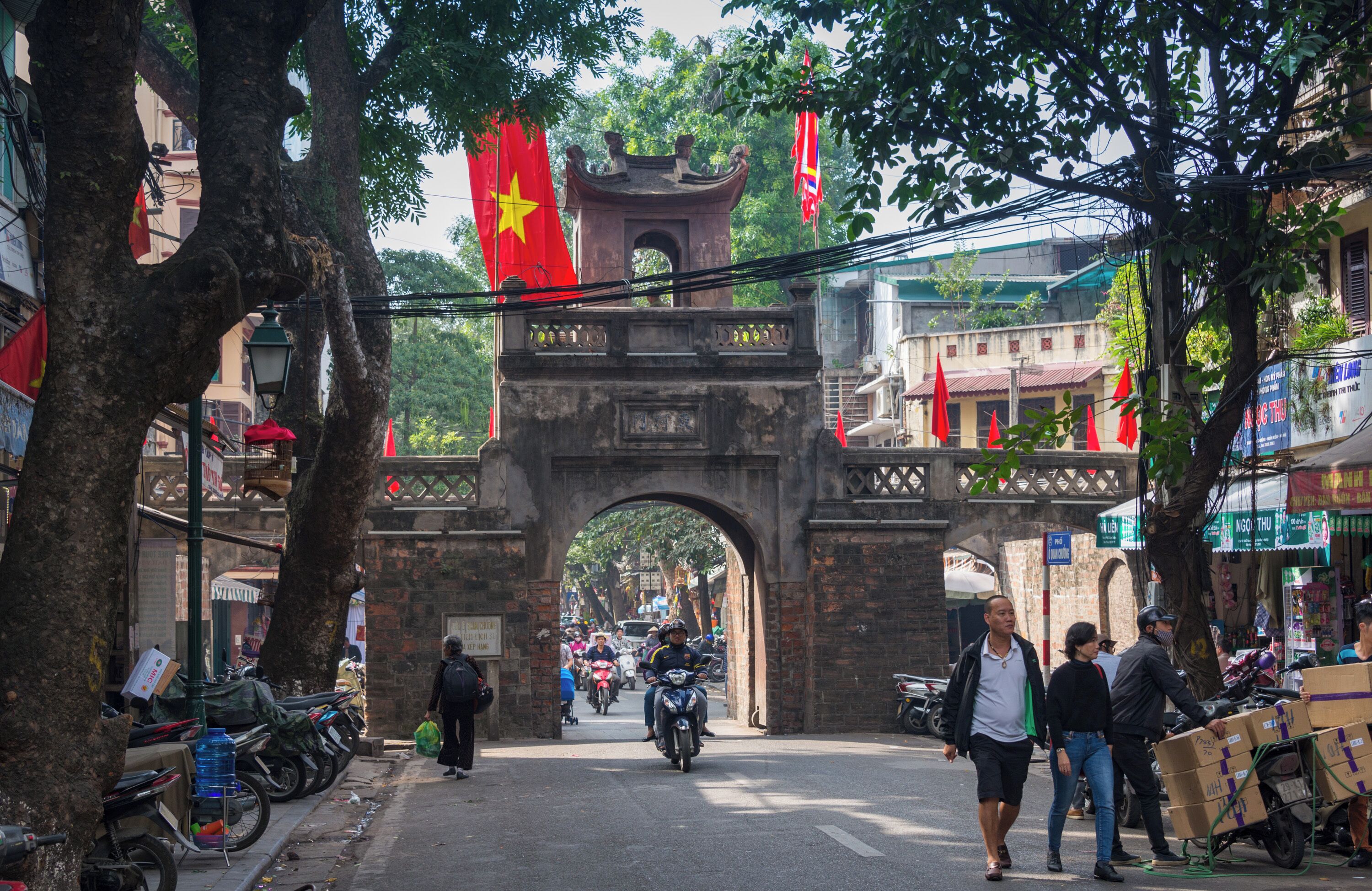 A street scene with a traditional archway, bicycles, and pedestrians.