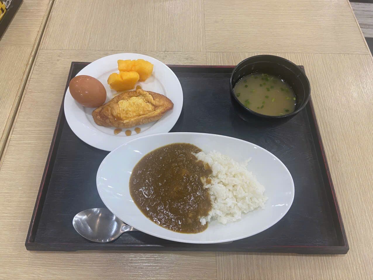 Una bandeja con arroz, curry, un huevo cocido y un tazón de sopa.