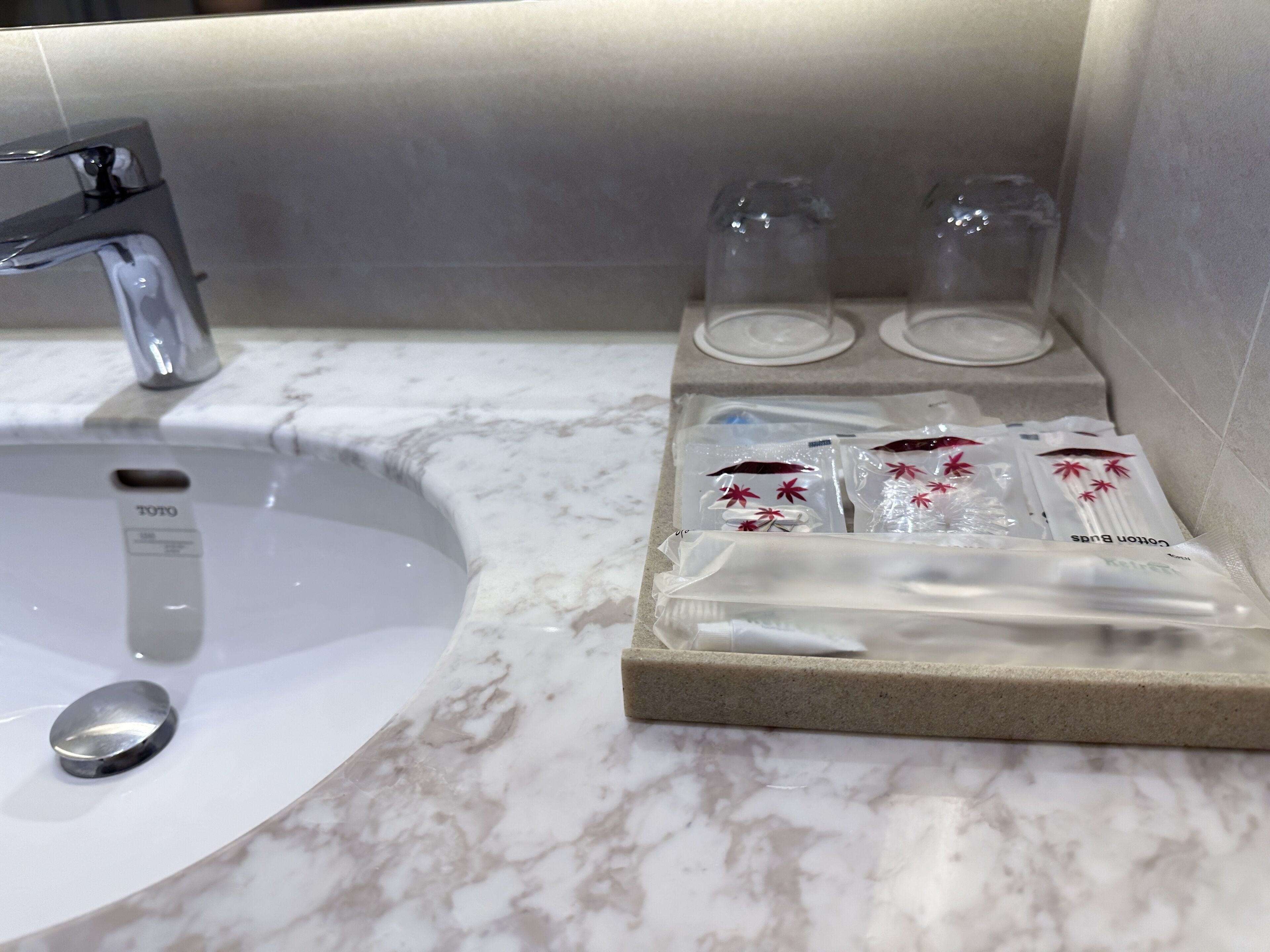 A bathroom with a white sink, a mirror, and a shelf with toiletries.
