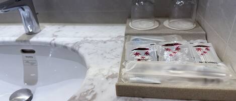 A bathroom with a white sink, a mirror, and a shelf with toiletries.