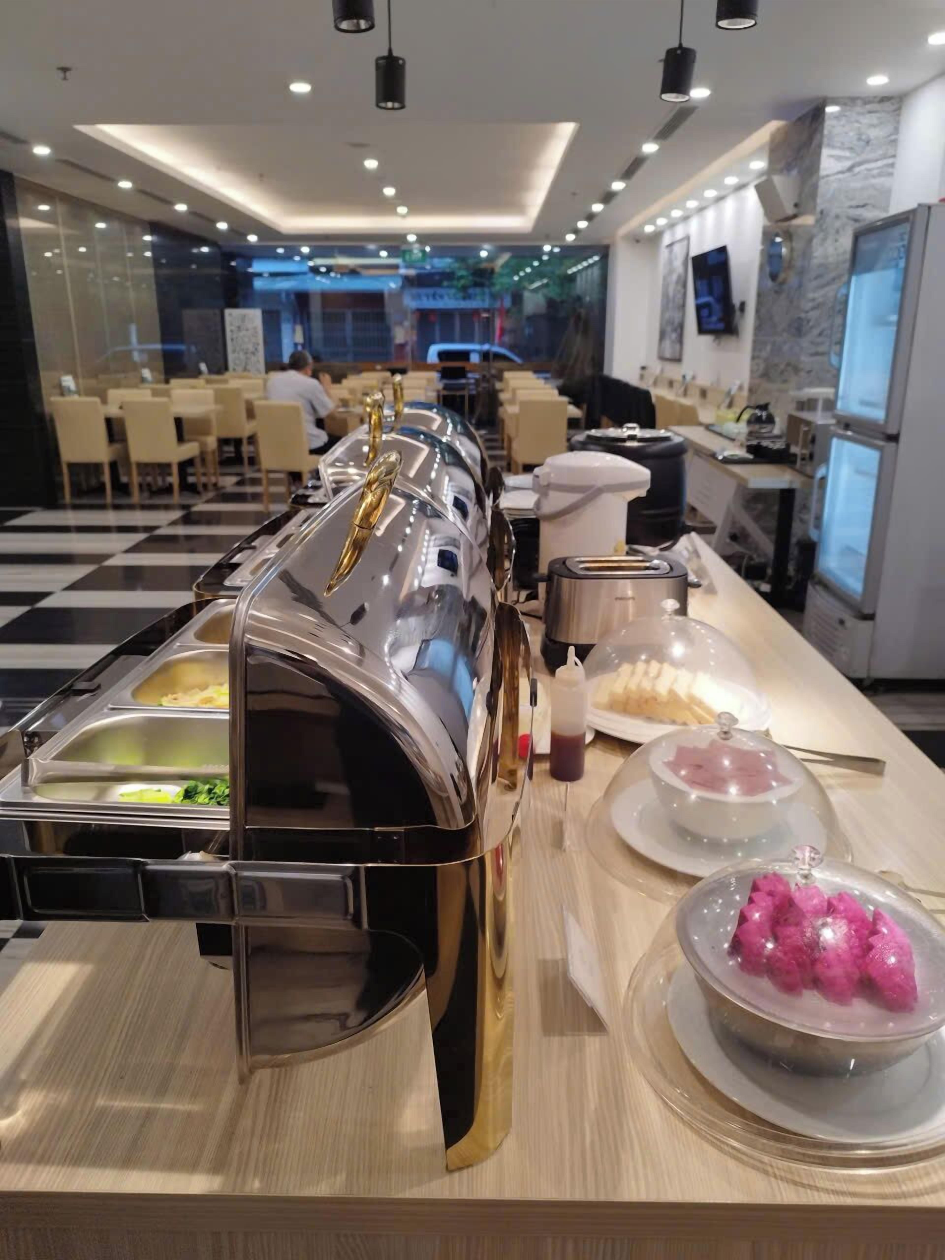 Un espace buffet proposant différents stands de nourriture, notamment un bar à salades, un stand de plats chauds et un espace dédié aux desserts.