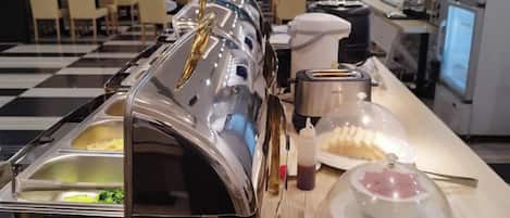 Un espace buffet proposant différents stands de nourriture, notamment un bar à salades, un stand de plats chauds et un espace dédié aux desserts.