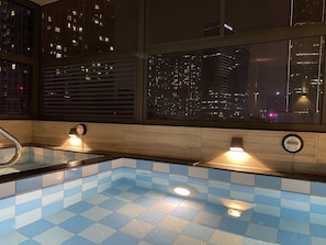 A modern bathroom with a blue-tiled floor, a built-in shower, and a window with a cityscape view at night. - HOTEL YAH HANOI (Hanoi)