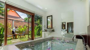 A bathroom with a large window, a bathtub filled with water and flowers, and a sink with a mirror above it. - Nita By Vo Private Pool (Siem Reap)