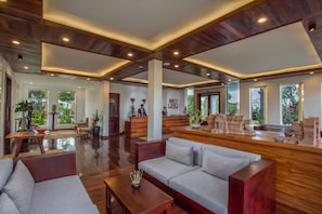 A spacious lobby with a reception desk, seating area, and large windows offering views of the outdoors.