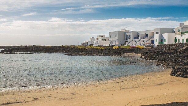 A coastal building with a beach in the foreground.