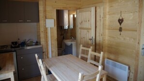 Een houten cabin met een keukenhoek, een eettafel en een badkamer.