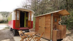 Een kleine houten hut met een rode en witte camper ernaast.